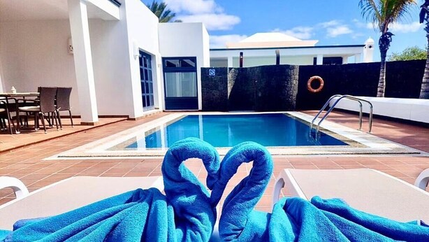 A poolside area with lounge chairs and a towel arranged in a heart shape. - Villas Mamma Mia  A pool heat Private (Castillo del Aguila)