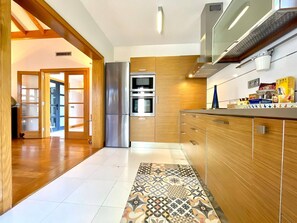 A modern kitchen with wooden cabinets, stainless steel appliances, and a patterned tile floor. - Playas Blanca Pool Private Villas (Playa Blanca)