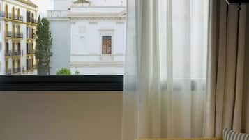 A room with a sofa, a table, and a window with sheer curtains.