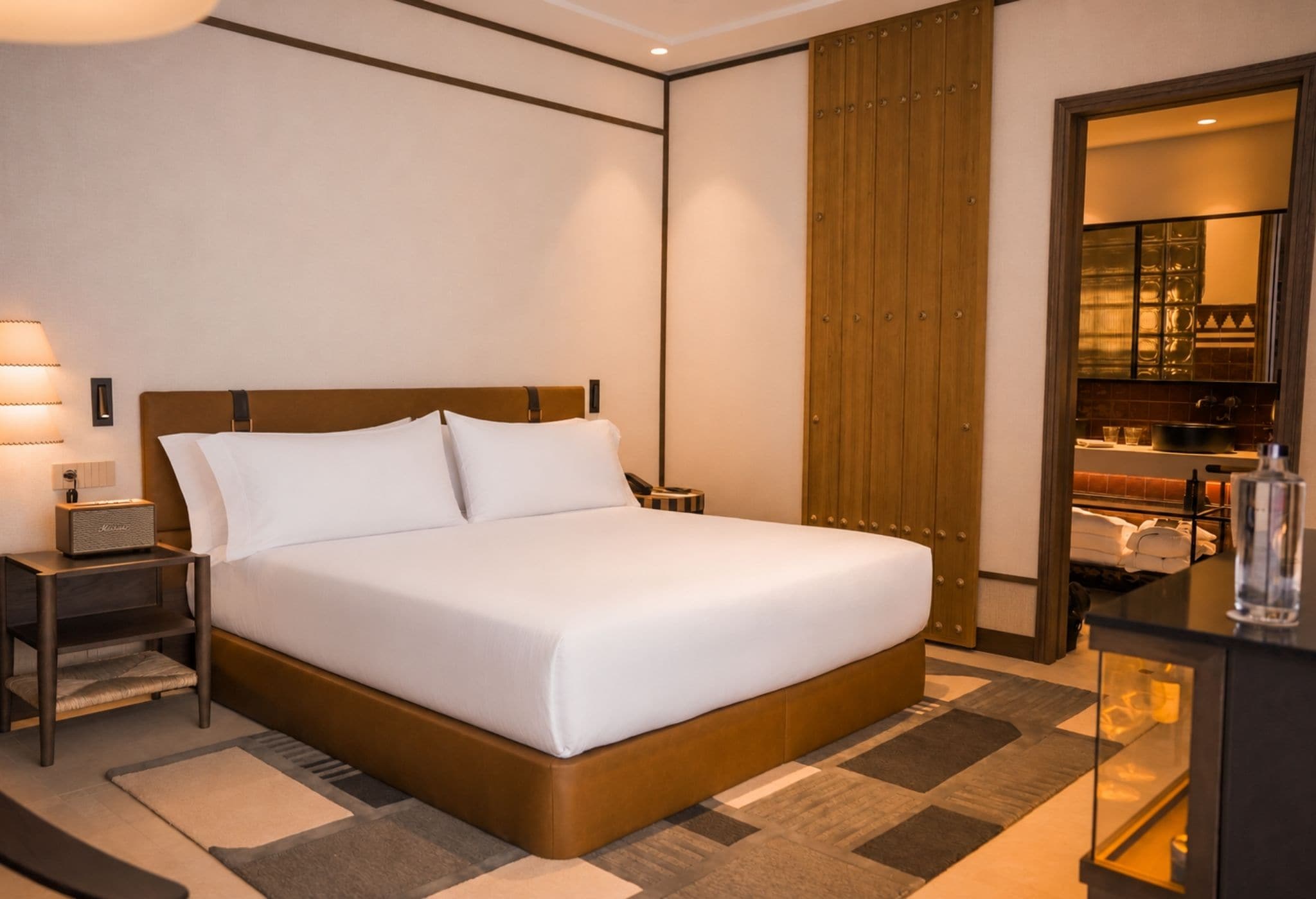 Une chambre d’hôtel avec un grand lit, des tables de chevet, une lampe, une armoire et une vue sur la cuisine.