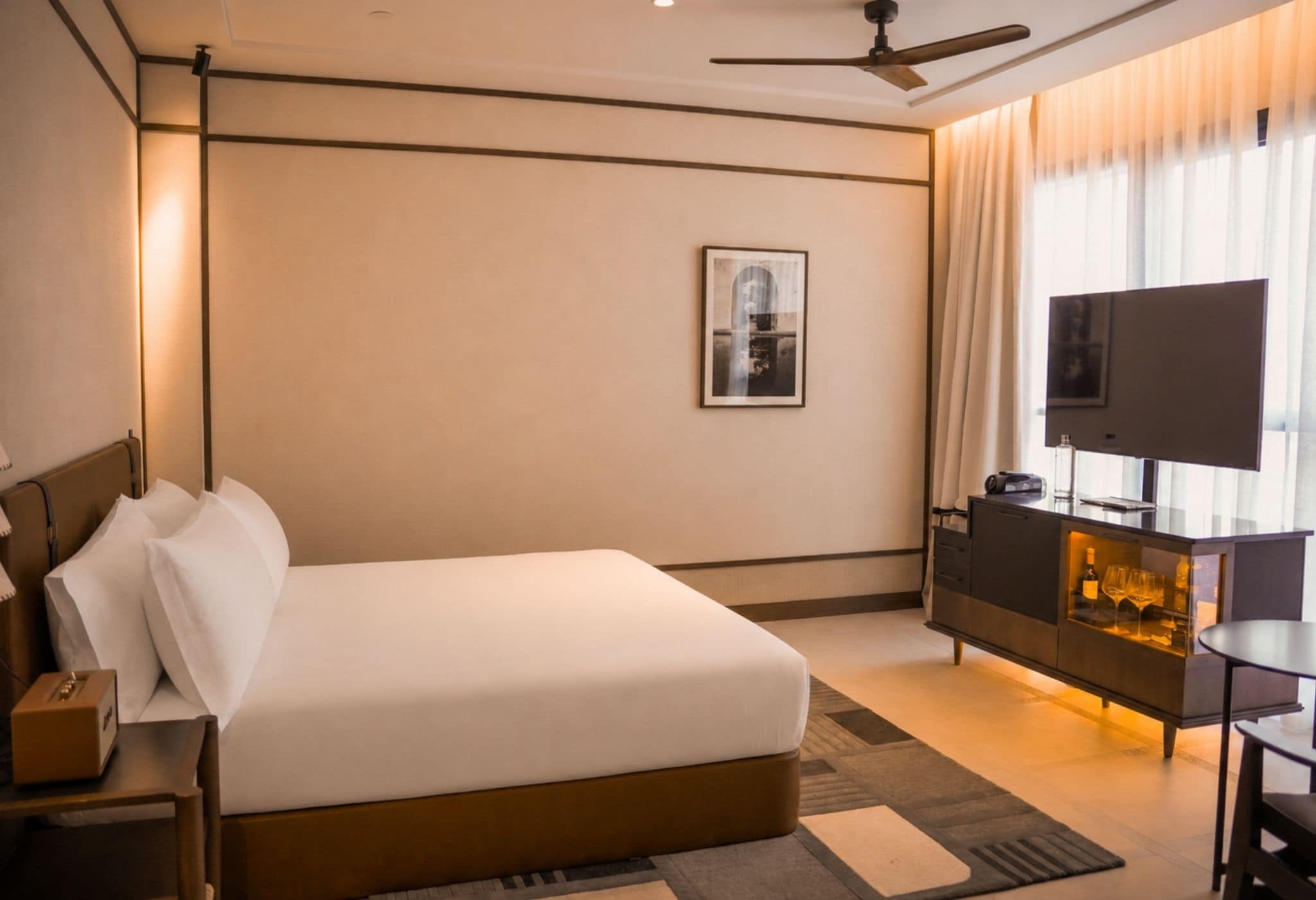 Una habitación de hotel con cama, escritorio, televisor y minibar.