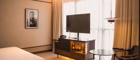 Une chambre d’hôtel équipée d’un lit, d’une télévision, d’un minibar, d’un bureau et d’une chaise.