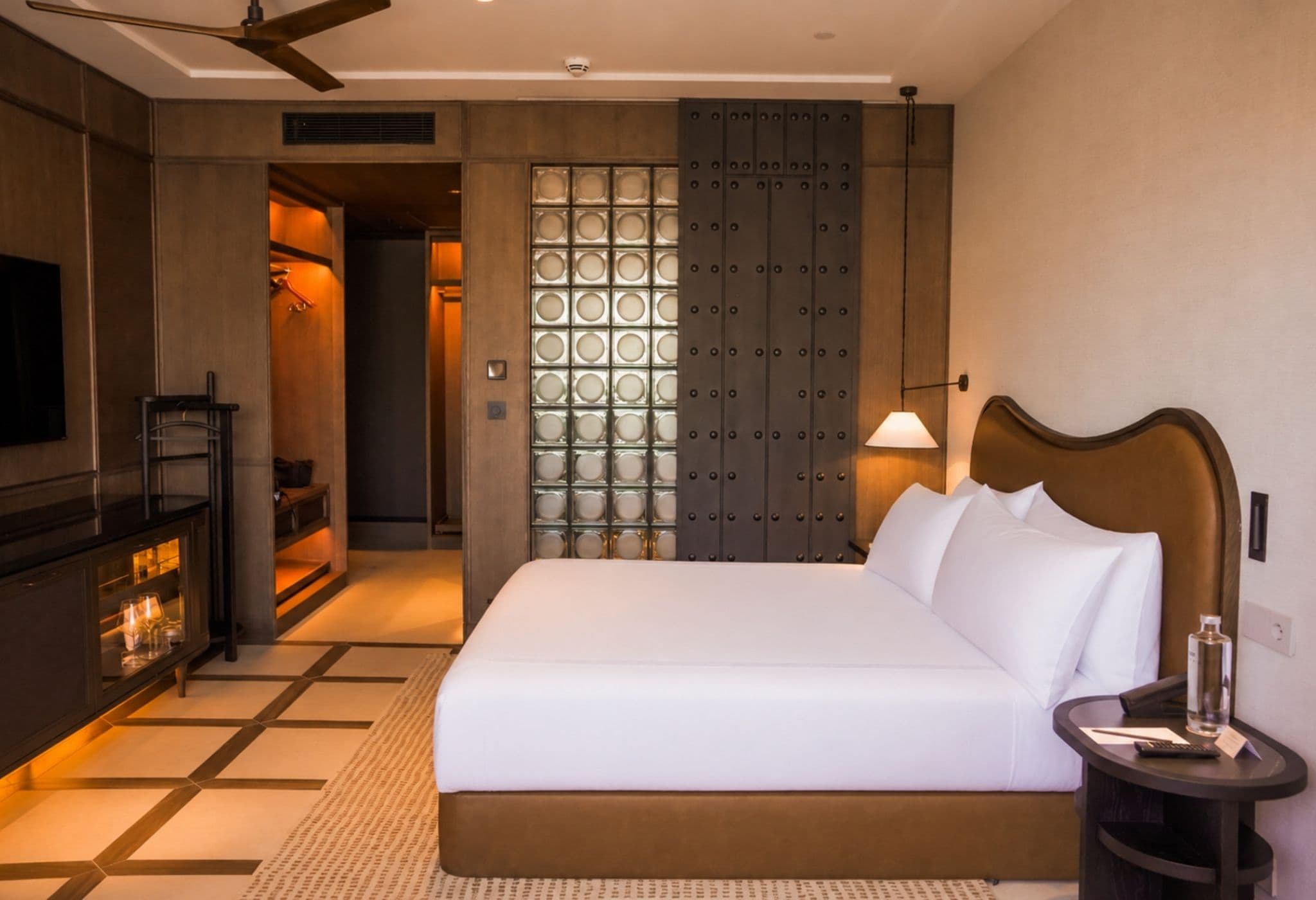 Une chambre d’hôtel avec un grand lit, une télévision, un minibar et une salle de bain dotée d’une paroi en verre.