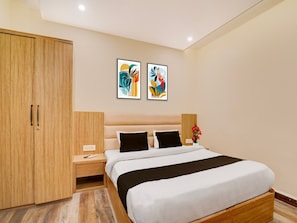 A modern bedroom with a large bed, wooden wardrobe, bedside tables, and two abstract paintings on the wall. - Townhouse Mahamrityunjay Dwar Ujjain (Ujjain)