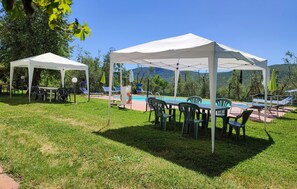 Zona exterior amb telt blanc, taules, cadires i piscina.