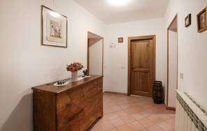 Ein Flur mit einem Holzschrank, einem gerahmten Bild an der Wand, einer Tür und einer Heizung.