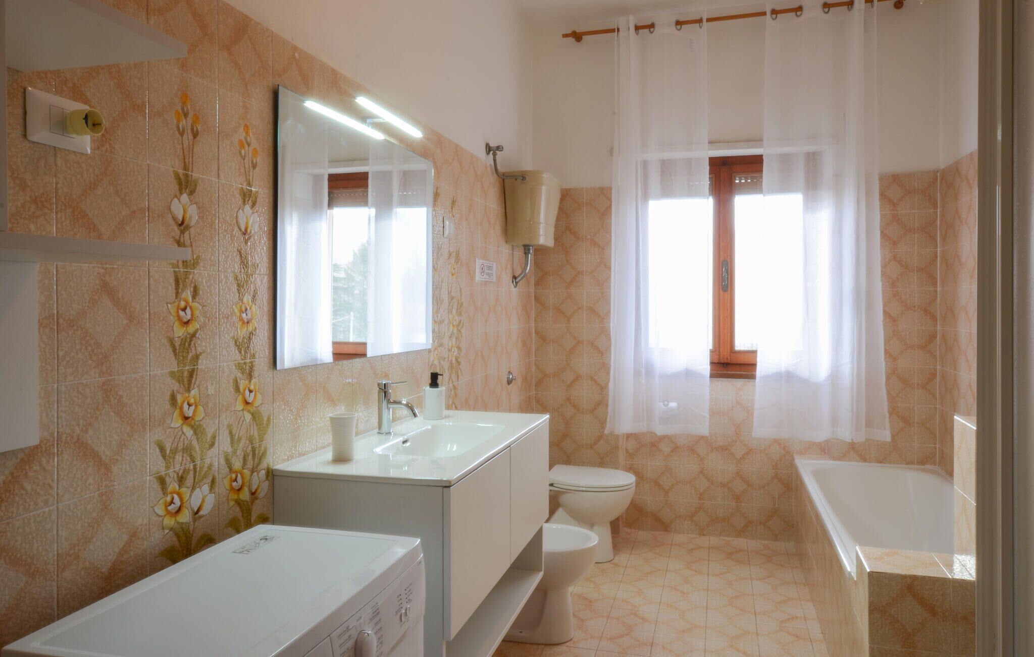 Une salle de bain avec un lavabo blanc, des toilettes et une baignoire.