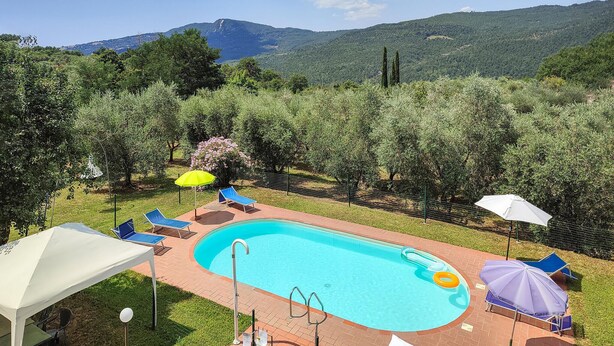 A swimming pool with a brick deck, surrounded by a fence and shaded by umbrellas. - Lovely home in Santa Fiora (Santa Fiora)