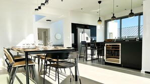 A modern kitchen with a central island, black cabinetry, and a large window providing natural light. - Architect-designed villa with sea view (Le Conquet)