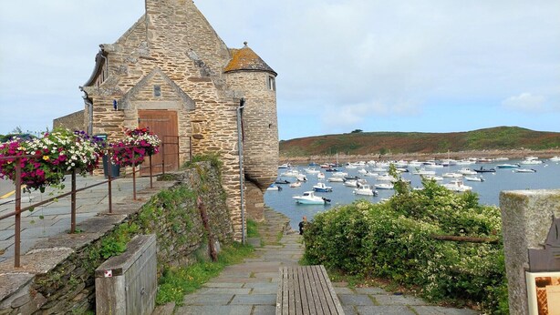 A stone building with a wooden door, steps leading to a harbor with boats. - Architect-designed villa with sea view (Le Conquet)