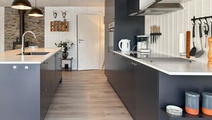A modern kitchen with a central island, wooden flooring, and a variety of kitchen appliances. - 3 bedroom awesome home in Farsø (Farsø)