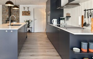Una cocina moderna con una isla central, piso de madera y una variedad de electrodomésticos.
