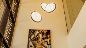 Decoração moderna com luminária de teto exclusiva e uma obra de arte emoldurada retratando uma cena antiga.