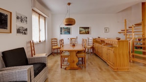 Un comedor con una mesa y sillas de madera, una lámpara colgante y cuadros en las paredes.