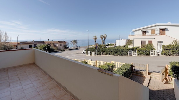 Un barrio residencial con balcón, calle y vista al mar.