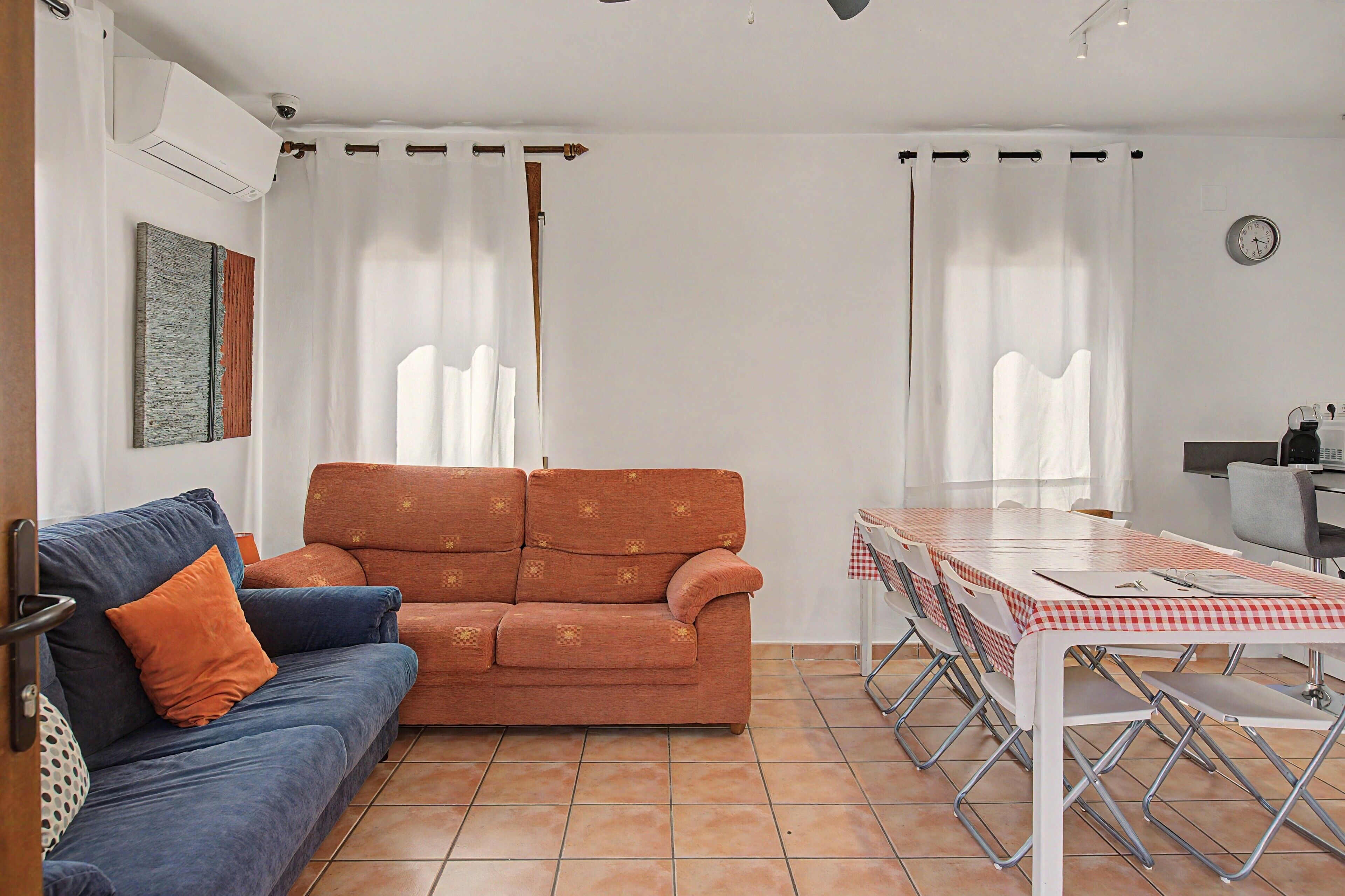 Una sala de estar con sofá, una mesa de comedor con sillas y una zona de cocina.