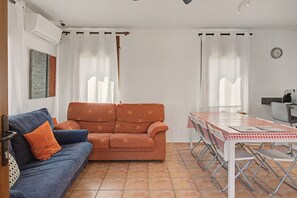 Un salon avec un canapé, une table à manger avec des chaises et un coin cuisine.