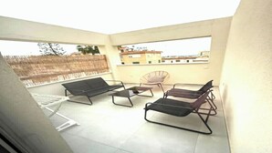 Ein Balkon mit einer Couch, zwei Stühlen und einem kleinen Tisch.