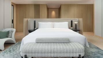 Una habitación de hotel moderna con una cama grande, mesitas de noche, un banco y vistas a la ciudad.
