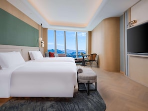 A hotel room with a large bed, a small table, a chair, and a TV.