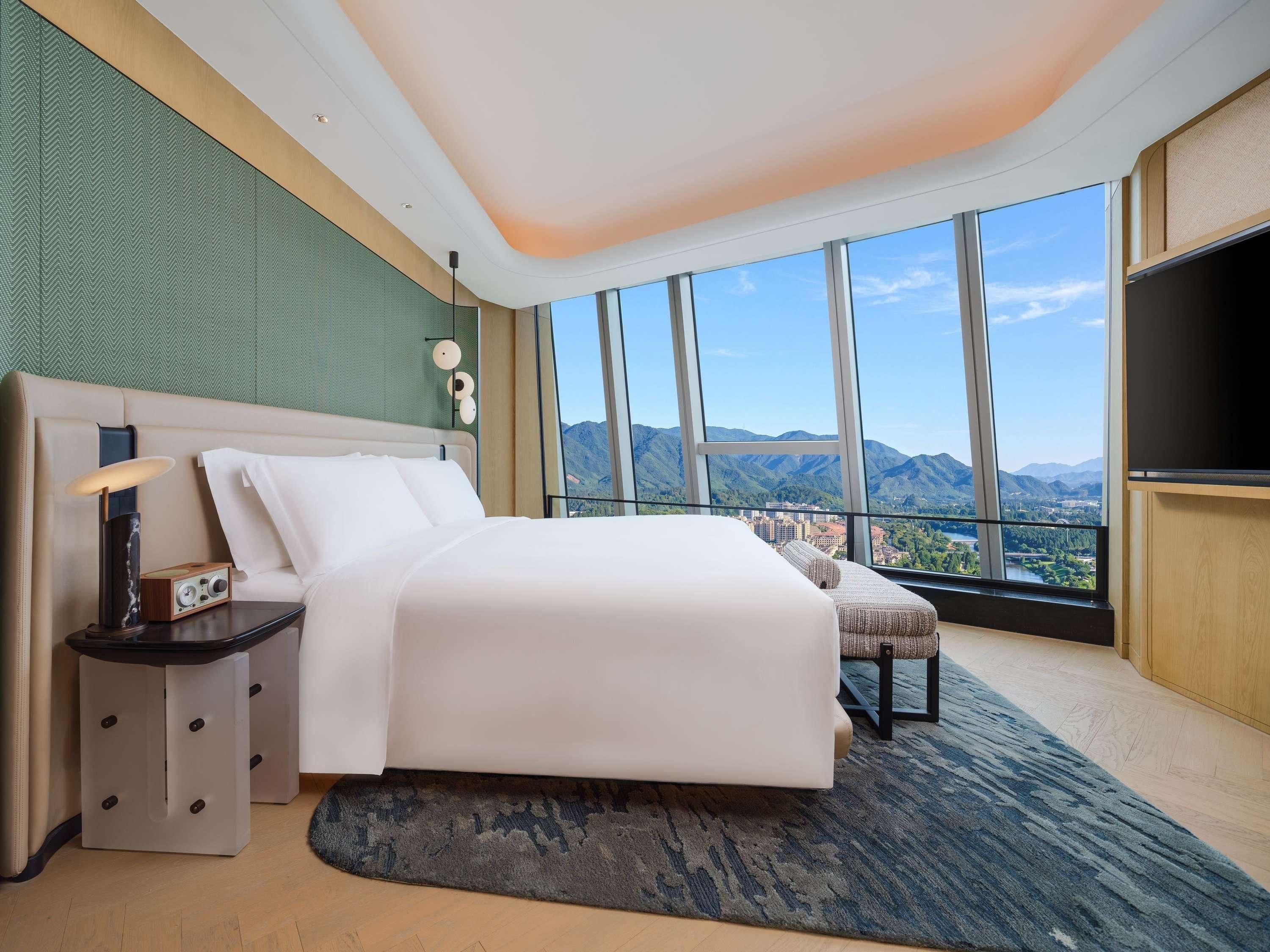 Une chambre d’hôtel moderne, dotée d’un grand lit, d’une table de chevet, d’une lampe et d’un téléviseur.