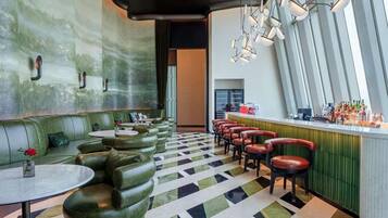 A bar area with a green cushioned seating arrangement, a patterned floor, and a bar counter with stools.