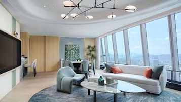 A modern living room with a sofa, chairs, a coffee table, and a large window offering a city view.