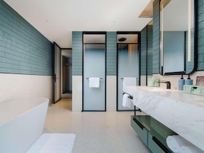 A modern bathroom with a large bathtub, a double vanity with a mirror, and a shower area.