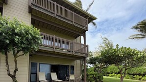 A two-story building with a balcony, outdoor seating area, and well-maintained lawn. - Oceanfront condo in Kapa’a, newly remodeled and ready for you to enjoy Kauai (Lihue)