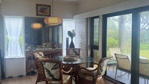 A dining area with wicker chairs, a glass table, and a view of the outdoors. - Oceanfront condo in Kapa’a, newly remodeled and ready for you to enjoy Kauai (Lihue)