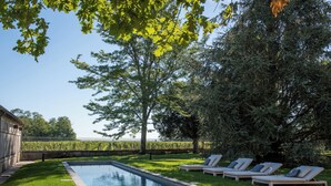 Une piscine avec des chaises longues et une pelouse.