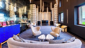 Un espace de détente moderne avec un meuble bleu, des sièges confortables et une grande fenêtre donnant sur un paysage agréable.