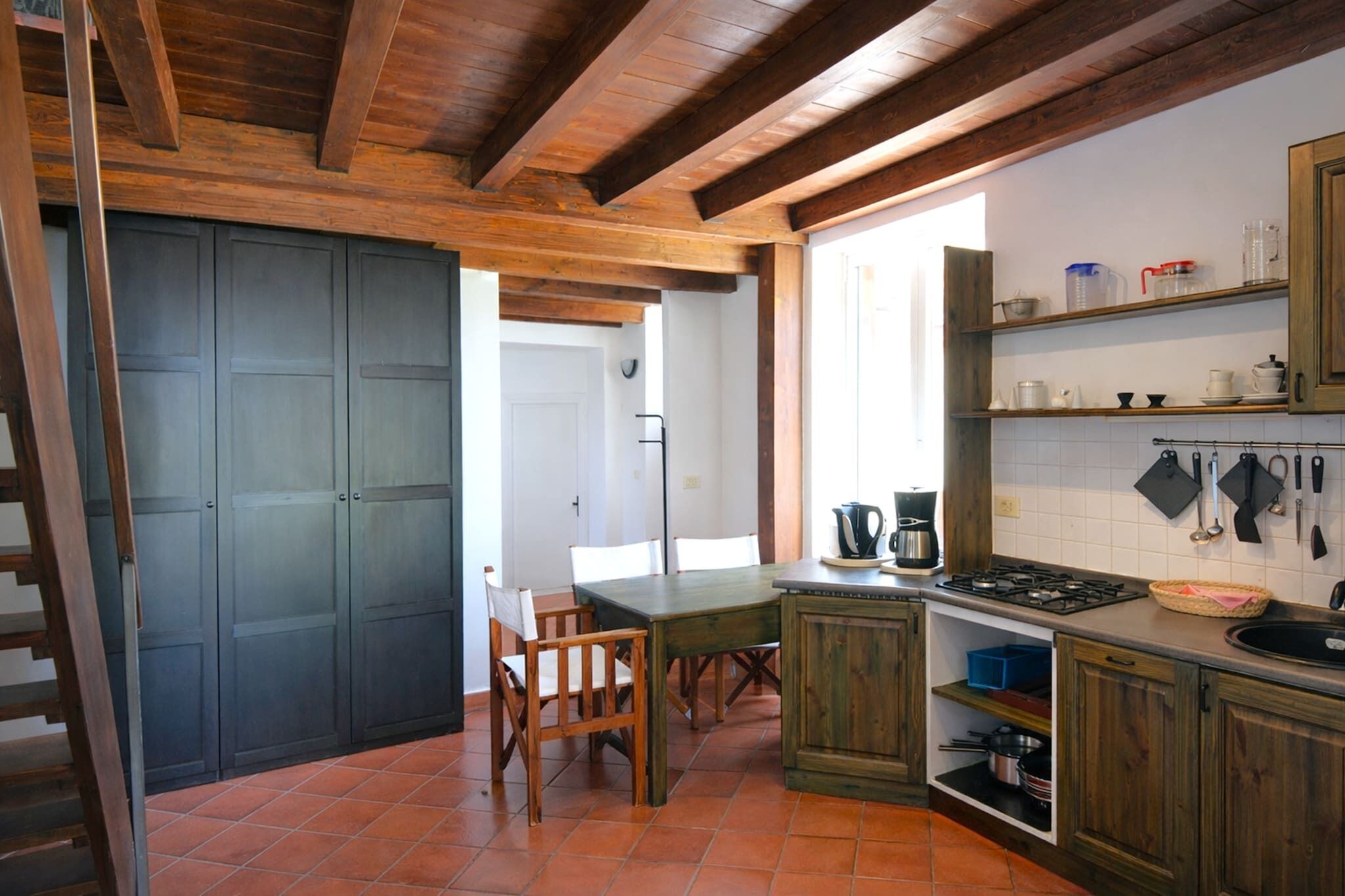 Una cocina con armarios de madera, salpicadero azulejado y un comedor con sillas y mesa.