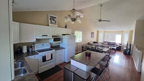 Cozinha espaçosa com armários brancos, micro-ondas, forno e área de refeições com mesa e cadeiras.