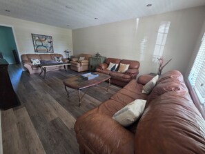 A living room with a brown leather sofa, a coffee table, and a painting on the wall.