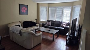 Uma sala de estar com sofá seccional, mesa de centro e televisão.