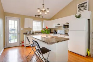 A modern kitchen with white cabinets, a central island, and a built-in microwave.