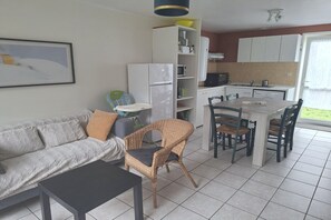 Un espace de vie compact comprenant un canapé, une table à manger, des chaises, un réfrigérateur et un coin cuisine.