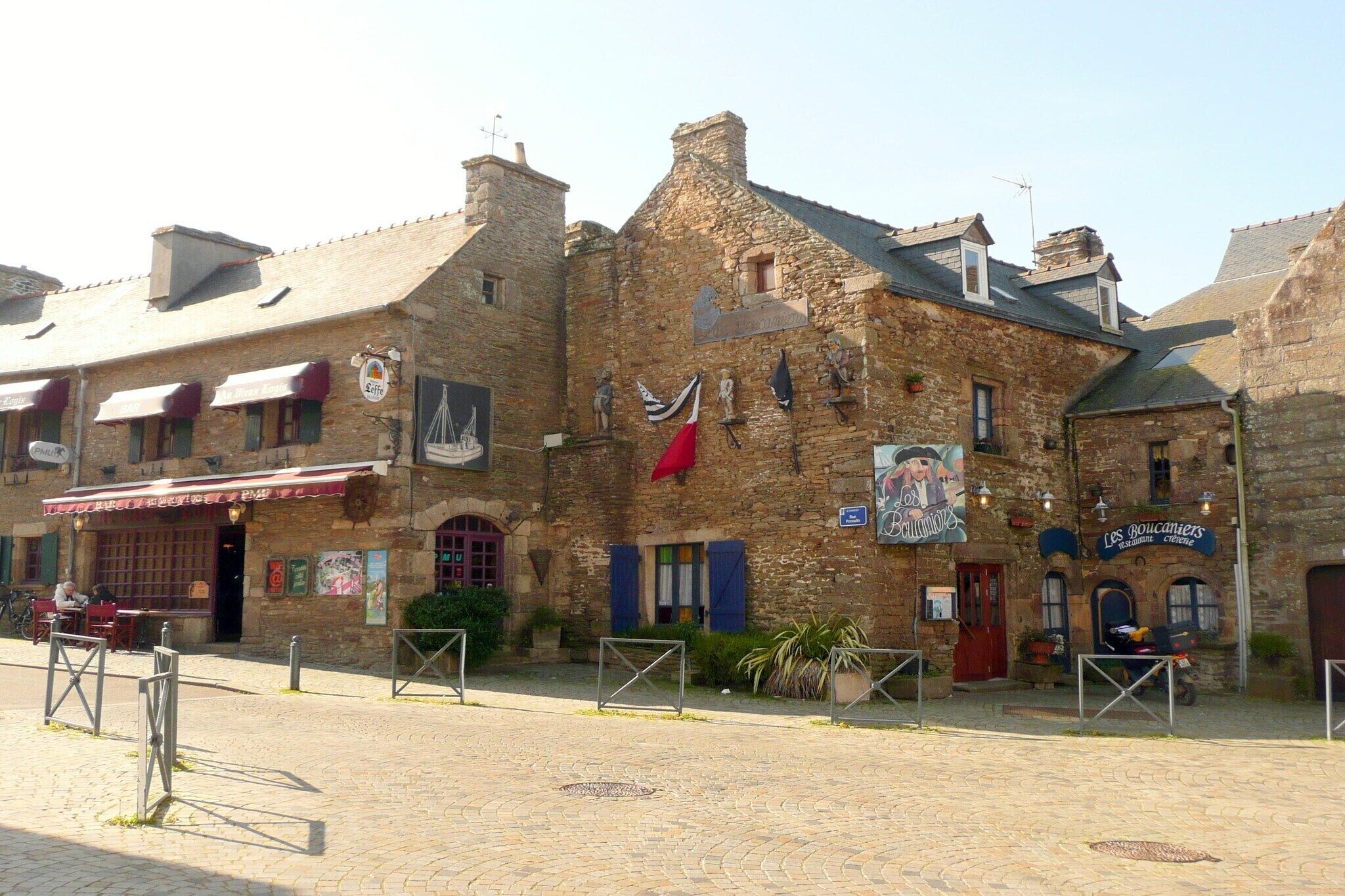 Ein Steinhaus mit mehreren Geschäften, darunter ein Restaurant und ein Laden mit dem Schild "Les bouquinistes".