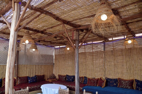 A room with a thatched roof, woven furniture, and hanging light fixtures.