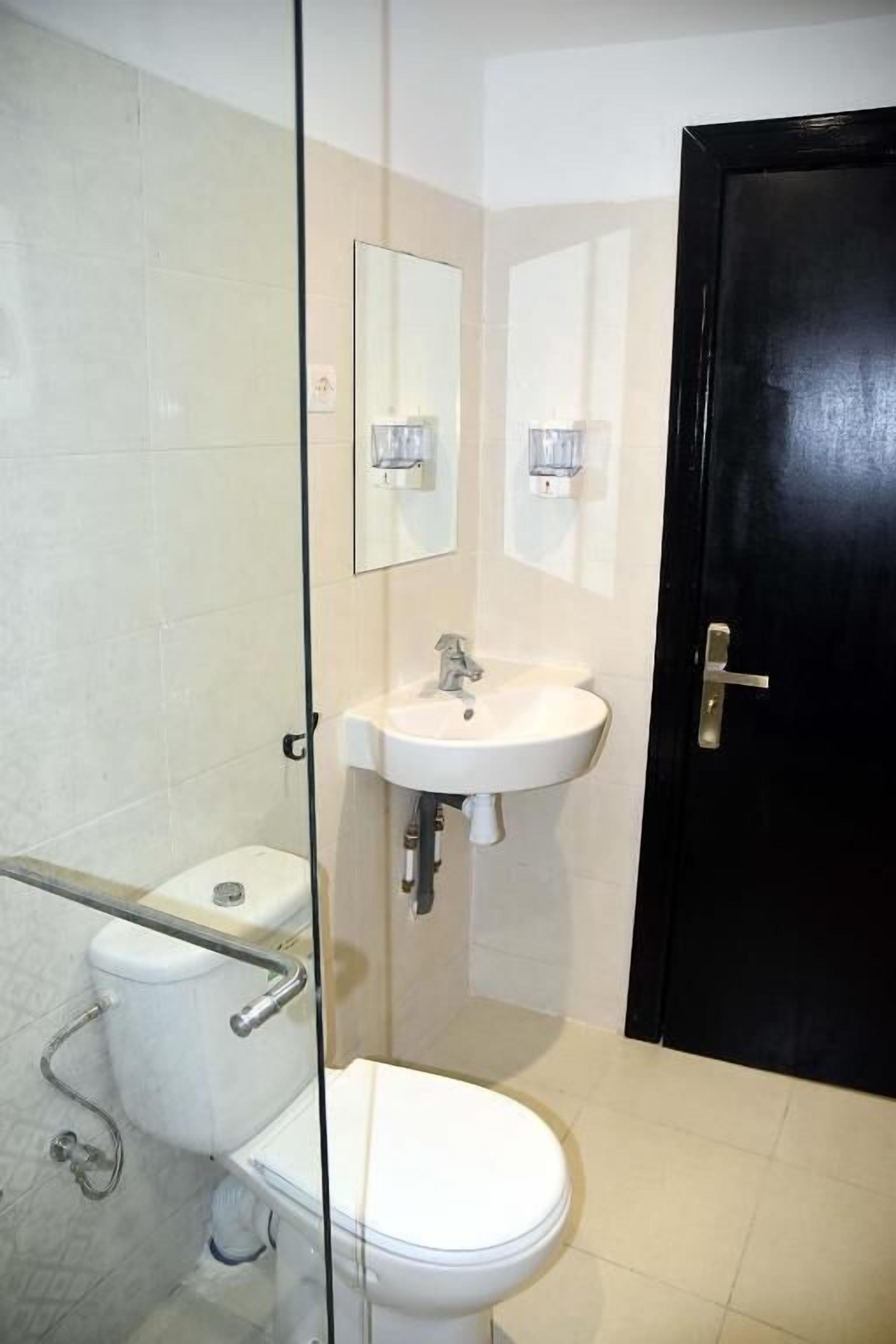 A bathroom with a toilet, sink, and mirror.