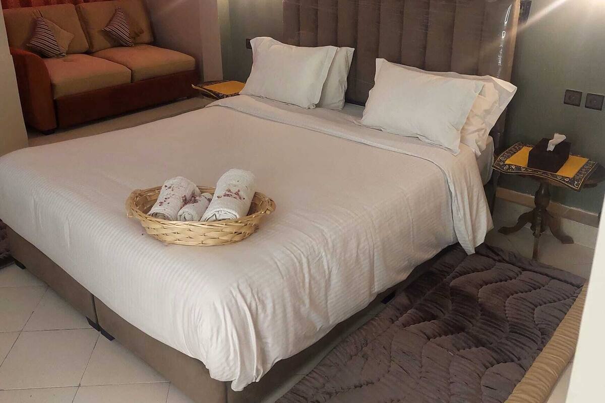 A hotel room with a large bed, a sofa, and a small table with a telephone.