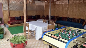 Een terras met een tafelvoetbaltafel, een bank en een tafel met stoelen.