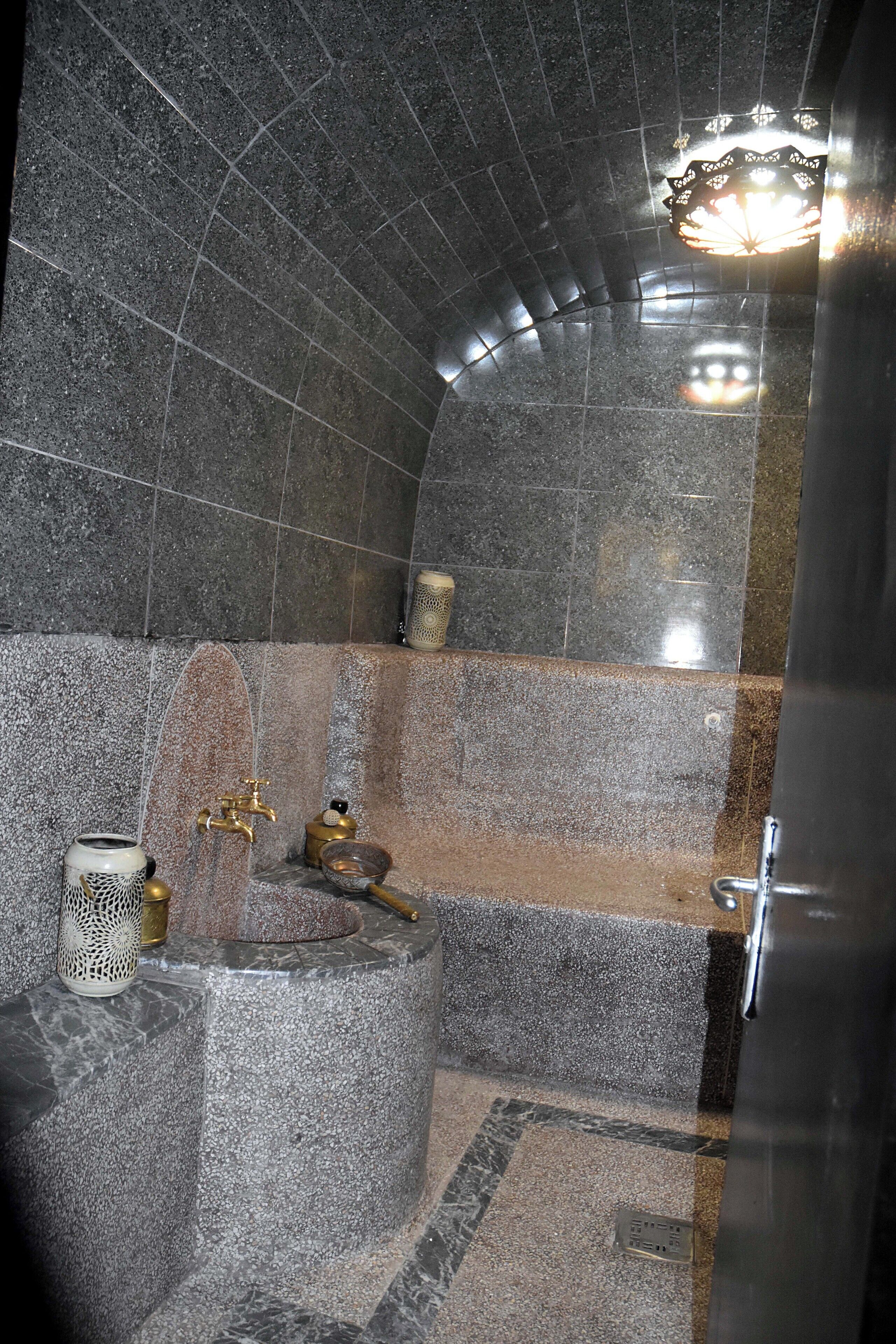 A bathroom with a stone wall, a sink with a gold faucet, and a decorative candle holder.