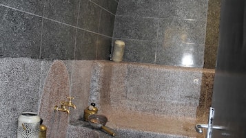 A bathroom with a stone wall, a sink with a gold faucet, and a decorative candle holder.