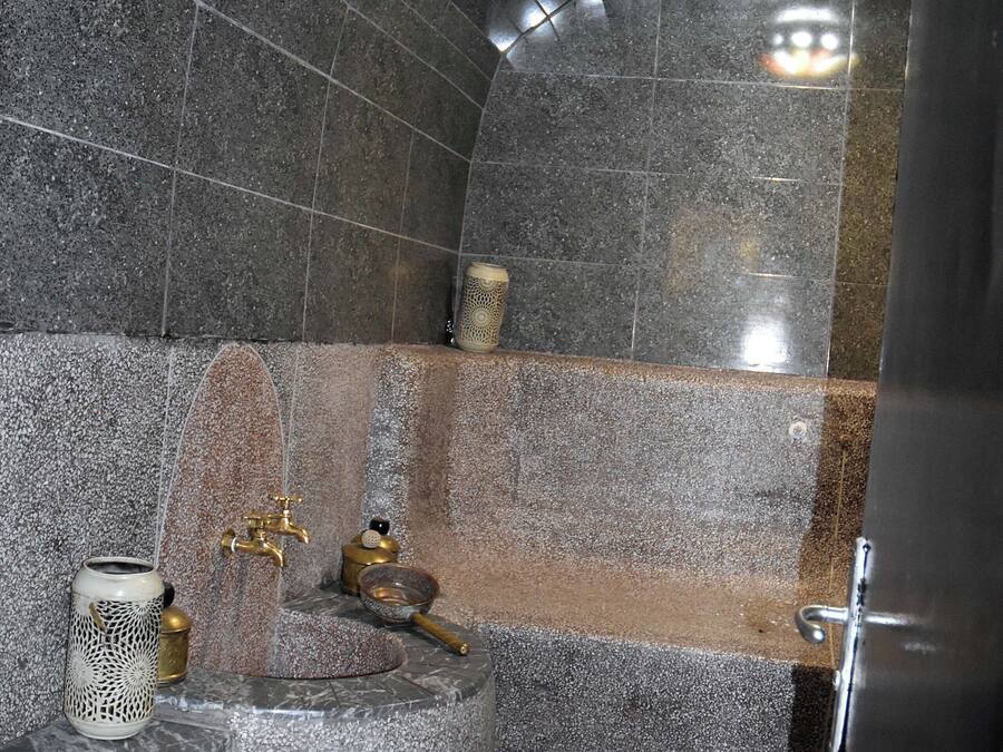 A bathroom with a stone wall, a sink with a gold faucet, and a decorative candle holder.