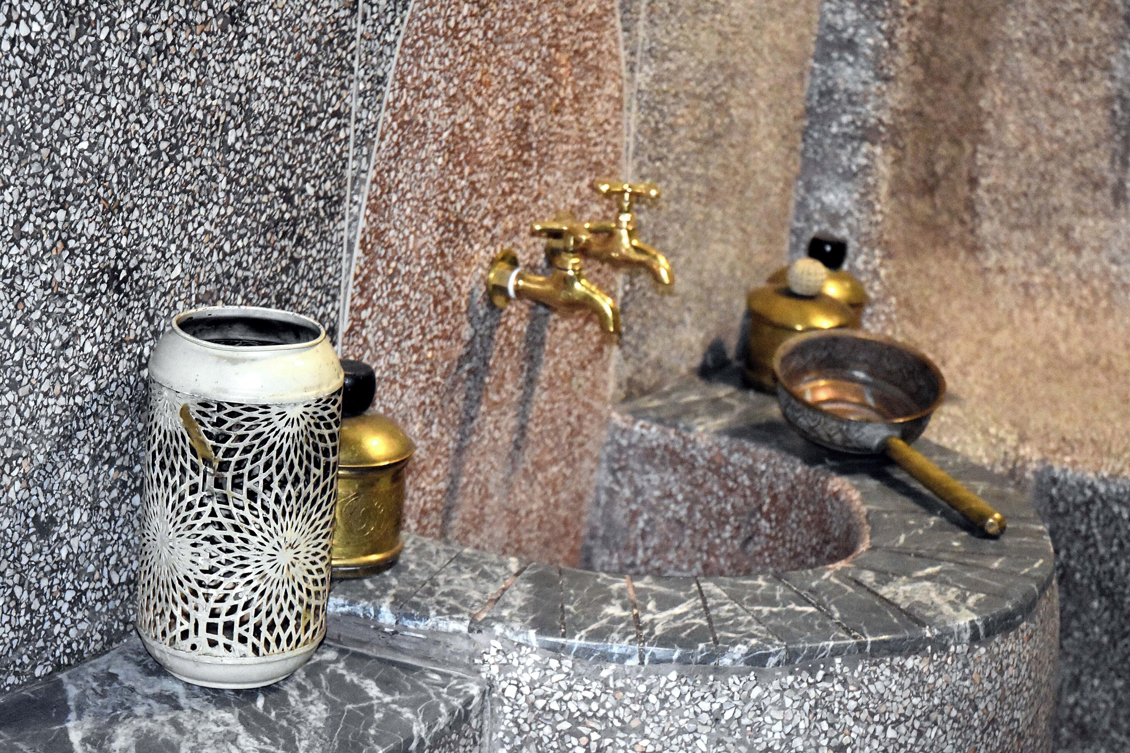A bathroom with a marble sink, a decorative metal candle holder, and a brass faucet.