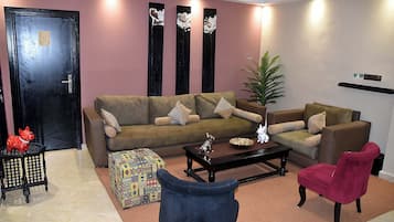 A living room with a sofa, armchairs, a coffee table, and decorative items.