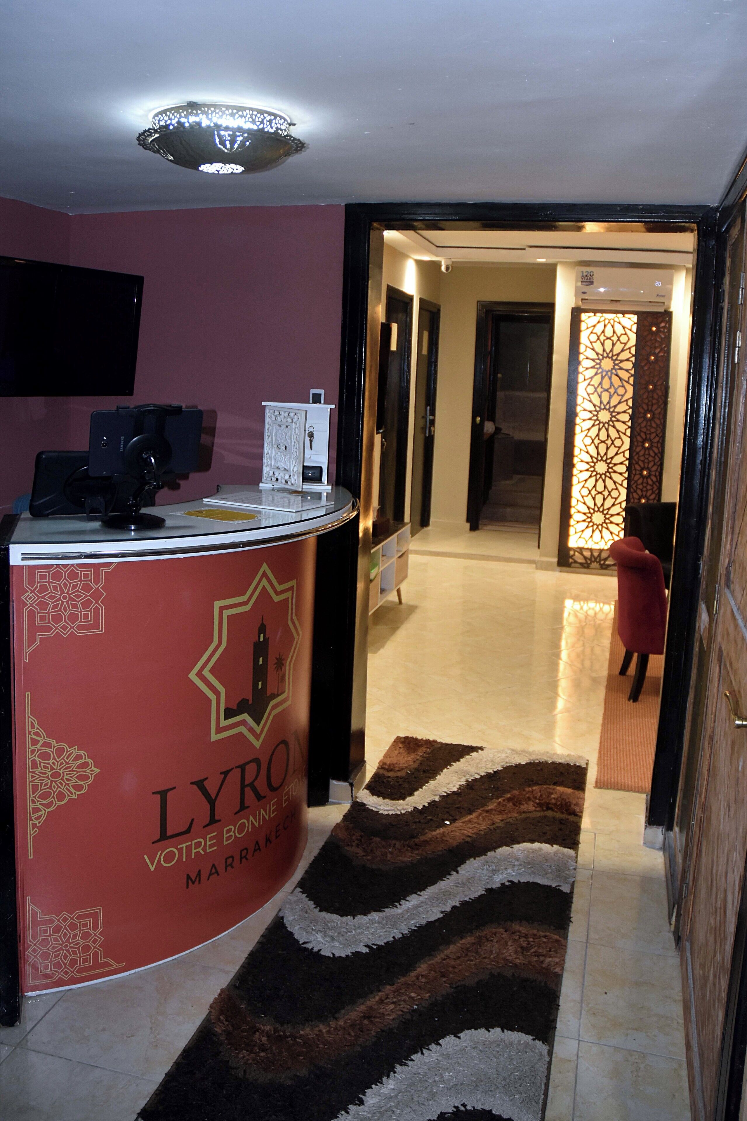 A reception area with a red counter labeled "LYRO VOTRE BONNE ETEIN MARRAKECH".