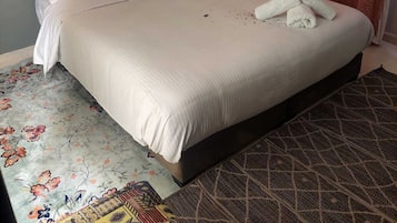 A hotel room with a large bed, a headboard, a wall-mounted light, and a patterned rug.